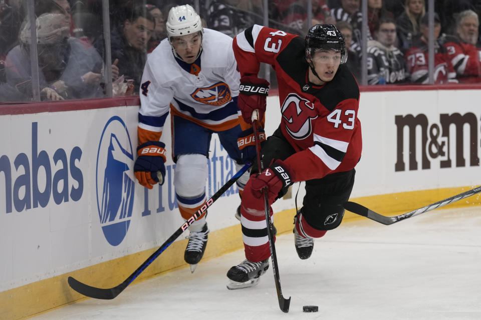 New Jersey Devils' Luke Hughes, right, controls the puck as New York Islanders' Jean-Gabriel Pageau looks on during the first period of an NHL hockey game in Newark, N.J., Tuesday, Nov. 28, 2023. (AP Photo/Seth Wenig)