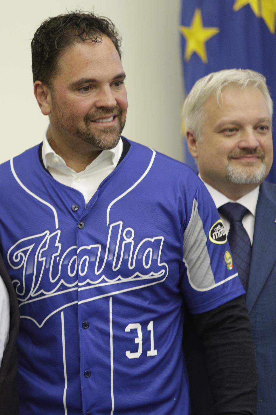 Hall of Fame catcher Mike Piazza shows his jersey during his presentation as Italy's national baseball team coach, at the Italian Olympic Committee headquarters in Rome, Friday, Nov. 29, 2019. At left is the President of the Italian Baseball Federation Andrea Marcon. (AP Photo/Alberto Pellaschiar)