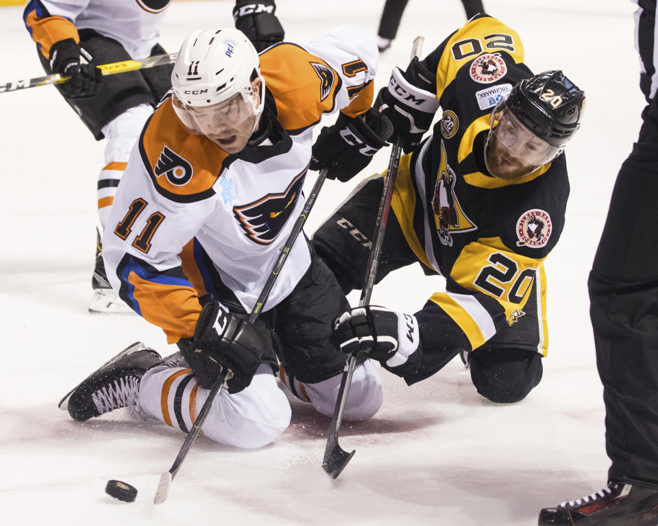FILE - In this March 16, 2019, file photo, Lehigh Valley Phantoms' Steven Swavely (11) moves the puck past the Wilkes-Barre/Scranton Penguins' Jarrett Burton after a faceoff during an AHL hockey game at Mohegan Sun Arena in Wilkes-Barre, Pa. The American Hockey League has canceled the rest of its season because of the coronavirus pandemic. President and CEO David Andrews announced the league ‘has determined that the resumption and completion of the 2019-20 season is not feasible in light of current conditions.’ The AHL's Board of Governors made that determination in a conference call Friday, May 8, 2020. (Christopher Dolan/The Citizens' Voice via AP, File)