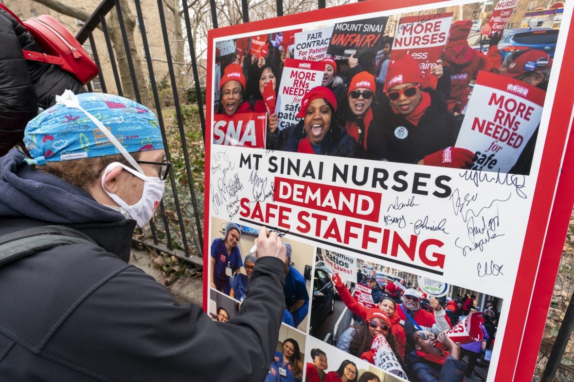 Zach Clapp, a nurse in the Pediatric Cardiac ICU at Mount Sinai Hospital signs a board demanding safe staffing during a rally by NYSNA nurses from NY Presbyterian and Mount Sinai, Tuesday, March 16, 2021, in New York. Negotiations to keep 10,000 New York City nurses from walking off the job headed Friday, Jna. 6, 2023, into a final weekend as some major hospitals braced for a potential strike by sending ambulances elsewhere and transferring such patients as vulnerable newborns. (AP Photo/Mary Altaffer, File)