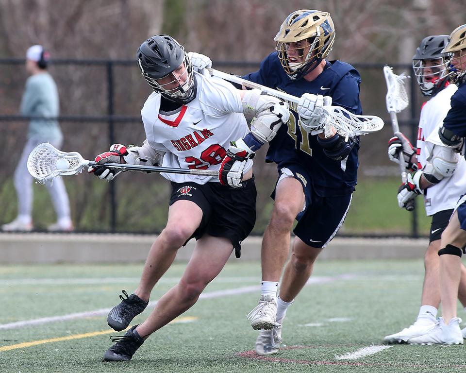 Hingham’s Owen Hoffman is checked by Needham’s John Hood while working his way to the Needham goal during first quarter action of their game against Needham at Hingham High School on Saturday, April 9, 2022. 