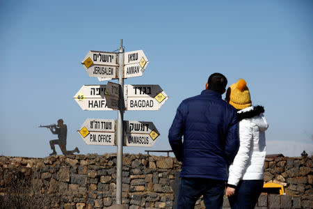 FILE PHOTO: A couple look towards signs pointing out distances to different cities, on Mount Bental, an observation post in the Israeli-occupied Golan Heights that overlooks the Syrian side of the Quneitra crossing, Israel January 21, 2019. REUTERS/Amir Cohen