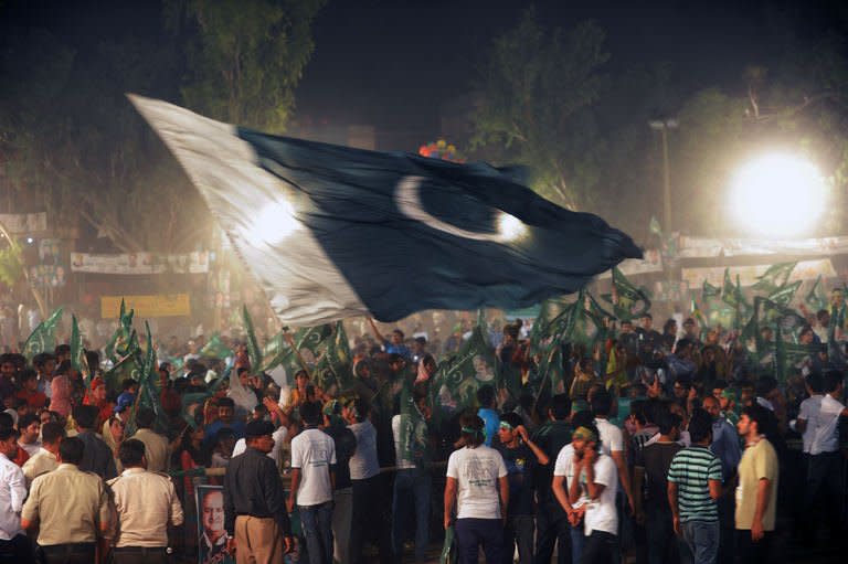 Supporters of Pakistani Prime Minister wave a giant Pakistani flag at a campaign closing rally in Lahore on May 9, 2013