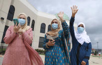 Saba Mahjabeen, right, and Gizman Mawi, center, waive as Sophia Baig looks on during a drive through Eid al-Fitr celebration outside a closed mosque in Plano, Texas, Sunday, May 24, 2020. Many Muslims in America are navigating balancing religious and social rituals with concerns over the virus as they look for ways to capture the Eid spirit this weekend. (AP Photo/LM Otero)