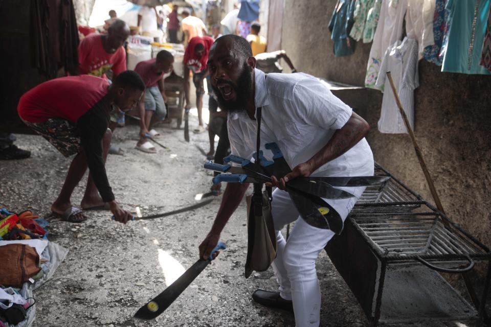 FILE - Nertil Marcelin, leader of a community group, and members of the community strike machetes against the ground as they support the "Bwa Kale" movement, an initiative to fight gangs seeking to take control of their neighborhood in the Delmas district of Port-au-Prince, Haiti, Sunday, May 28, 2023. (AP Photo/Odelyn Joseph, File)