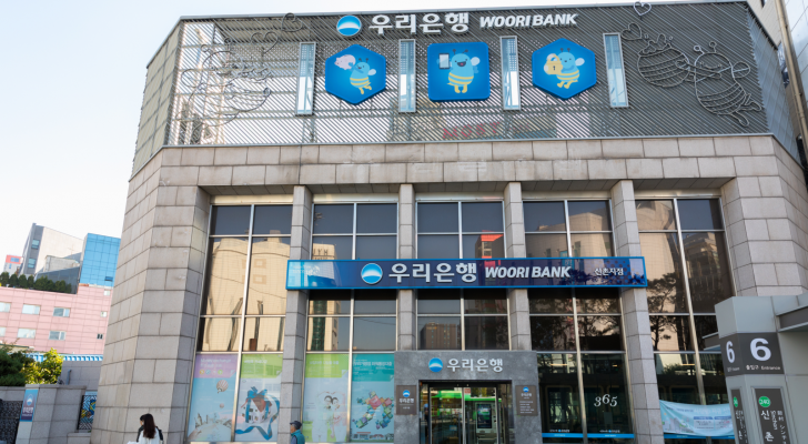 The logo for Woori Bank, owned by Woori Financial Group, is seen on a branch location. The building is decorated with bee illustrations.