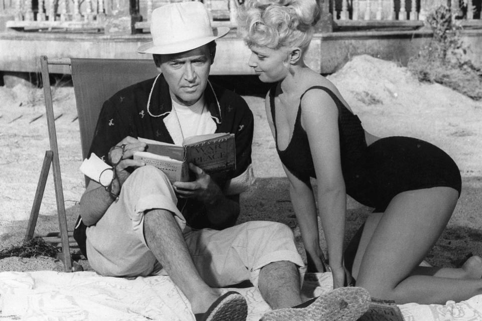 <p>James Stewart enjoys a beach read while spending time with actress Valerie Varda.</p>