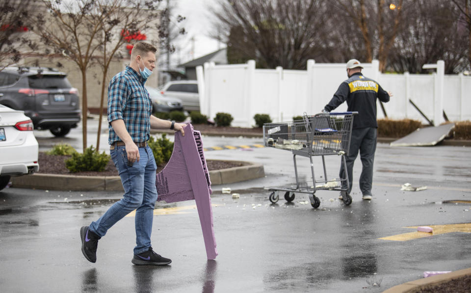 Kroger employees at the location on Scottsville Road in Bowling Green, Ky., help collect shopping carts blown around the parking lot and pick up debris after another tornado warning was issued late Saturday morning, Jan. 1, 2022, for Warren and surrounding counties, following the devastating tornadoes that tore through town on Dec. 11, 2021. Though the damage from Saturday's storm proved less catastrophic than the system that passed through in December, heavy rain and strong winds battered the area, causing damage along Cave Mill Road and the surrounding area. (Grace Ramey/Daily News via AP)