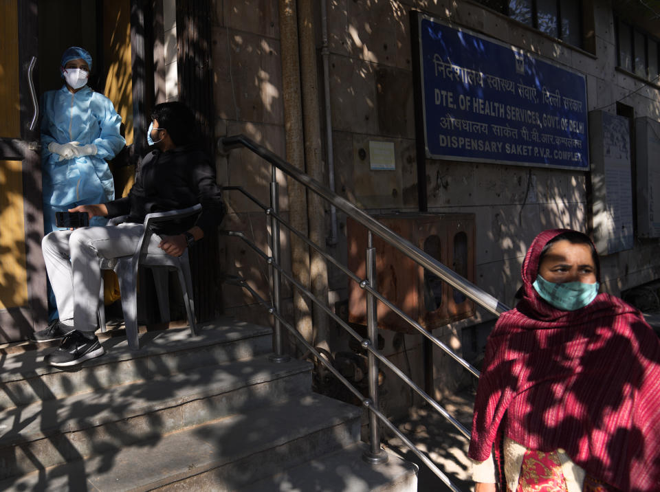 A woman waits for her Covid 19 antigen test result as other waits to get tested at a health center, in New Delhi, India, Friday, Jan. 28, 2022. Indian health officials said that the first signs of COVID-19 infections plateauing in some parts of the vast country were being seen, but cautioned that cases were still surging in some states. (AP Photo/Manish Swarup)