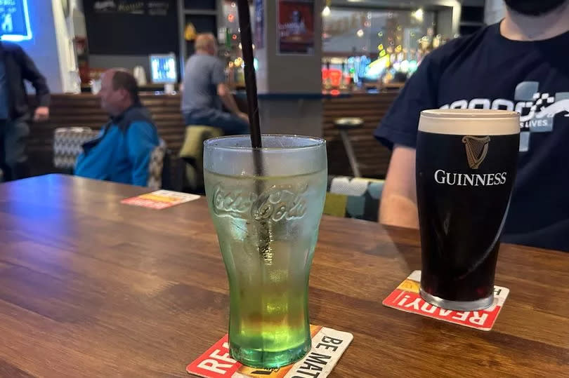 Photo shows two drinks with bar in the background