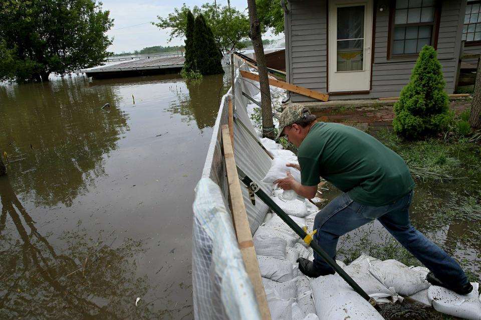 Alley Ringhausen uses sandbags to shore up the wall he and other volunteers built around the Riverview House in Elsah, Ill., as floodwater from the Mississippi River seeps through a makeshift barrier on Monday, May 6, 2019. (David Carson/St. Louis Post-Dispatch via AP)