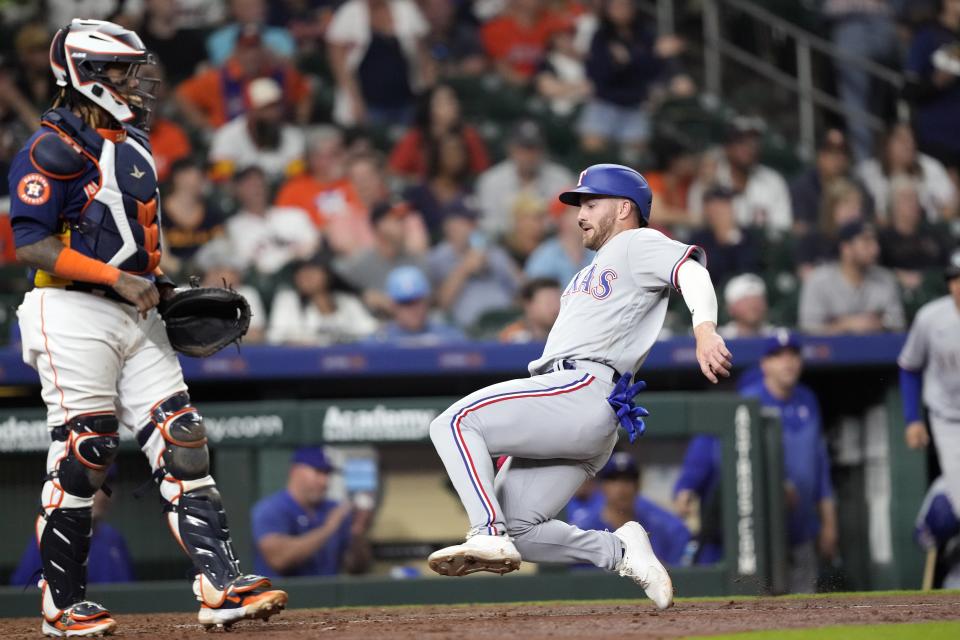 Texas Rangers' Robbie Grossman, right, scores as Houston Astros catcher Martin Maldonado stands at home plate during the eighth inning of a baseball game Sunday, April 16, 2023, in Houston. (AP Photo/David J. Phillip)