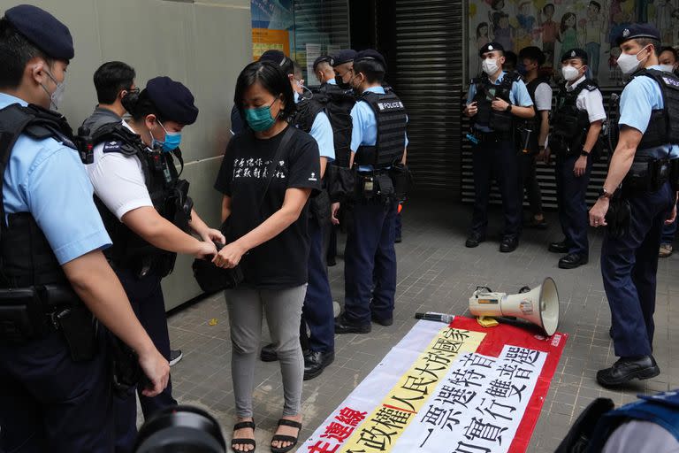 Una manifestante prodemocrática es registrada por agentes de policía mientras canta un eslogan contra la elección del jefe del Ejecutivo cerca de un colegio electoral en Hong Kong, el domingo 8 de mayo de 2022