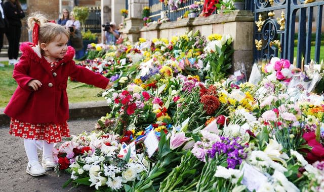 Abigail Glen. two, from Lisburn, lays flowers at the gates of Hillsborough Castle in Co Down