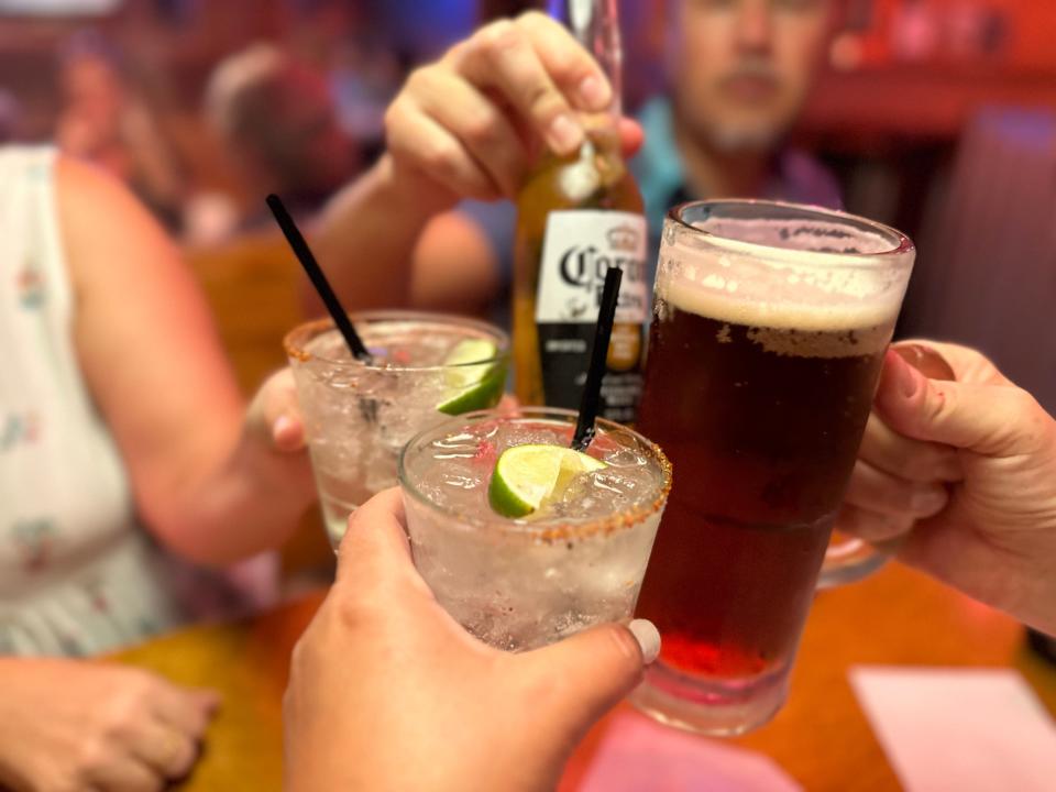 Four people cheersing beers and cocktails at a Texas Roadhouse