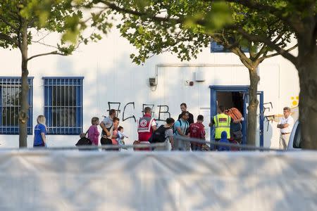 Aid workers bring asylum seekers to accommodation in a former home furnishings store in Heidenau August 22, 2015. The right-wing political party NPD organized a protest against bringing the asylum seekers to the facility on Friday. REUTERS/Axel Schmidt