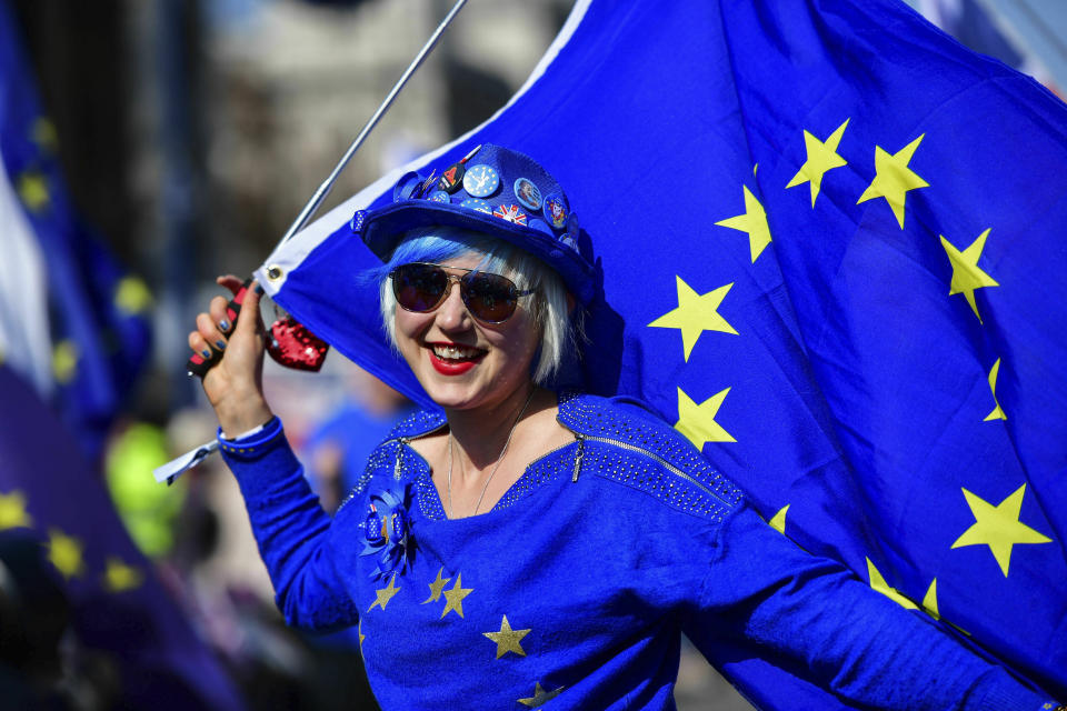 Madeleina Kay, Young European of the Year 2018 dressed in blue holds an EU flag and entertains the public while singing about Brexit outside the Houses of Parliament in Westminster, London, ahead of the latest round of debates in the House of Commons concerning Brexit issues, Monday April 1, 2019. (Rebecca Brown/PA via AP)