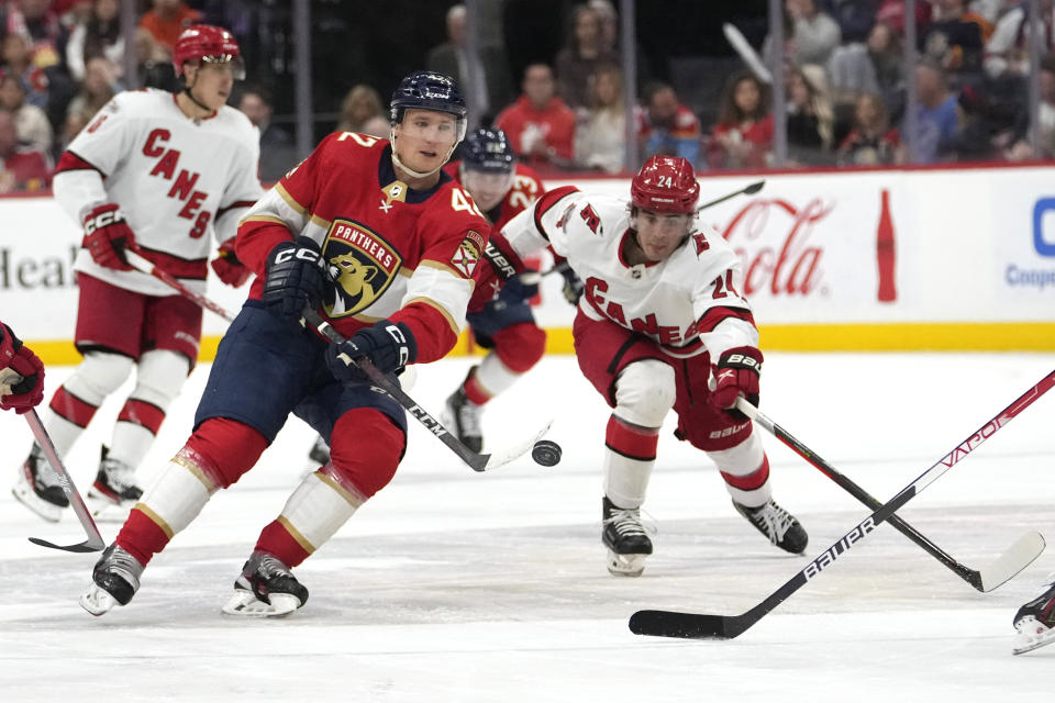 Florida Panthers defenseman Gustav Forsling (42) and Carolina Hurricanes center Seth Jarvis (24) chase the puck during the second period of an NHL hockey game Thursday, April 13, 2023, in Sunrise, Fla. (AP Photo/Lynne Sladky)