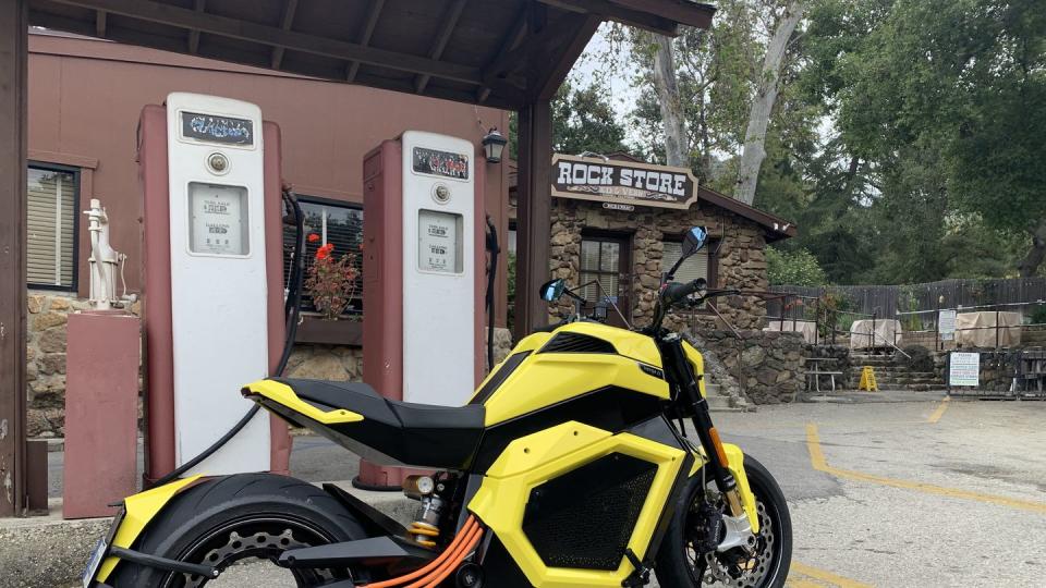 a yellow motorcycle parked in front of a gas station