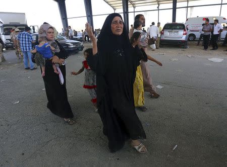 A woman reacts as families fleeing the violence in the Iraqi city of Mosul arrive at a checkpoint on the outskirts of Arbil, in Iraq's Kurdistan region June 10, 2014. REUTERS/Stringer