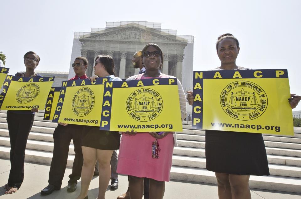 FILE - Representatives from the NAACP Legal Defense Fund stand outside the Supreme Court in Washington, June 25, 2013, awaiting a decision in Shelby County v. Holder, a voting rights case in Alabama. A U.S. Supreme Court decision a decade ago that tossed out the heart of the Voting Rights Act continues to reverberate across the country. Republican-led states continue to pass voting restrictions that, in several cases, would have been subject to federal review had the court left the provision intact. (AP Photo/J. Scott Applewhite, File)