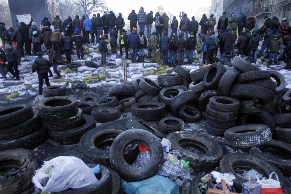 Protesters guard the barricade in front of riot police in Kiev, Ukraine, Friday, Jan. 24, 2014. Protesters on Friday seized a government building in the Ukrainian capital while also maintaining the siege of several governors’ offices in the country’s west, raising the pressure on the government. (AP Photo/Darko Vojinovic)