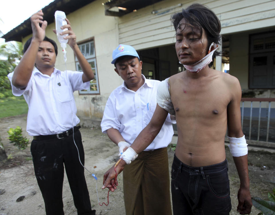 In this Tuesday, Oct. 1, 2013 photo, an injured Rakhine man, right, is helped to go to hospital in Thandwe, Rakhine State, western Myanmar. Buddhist mobs killed a 94-year-old Muslim woman and torched more than 70 homes on Tuesday as sectarian violence again gripped Myanmar's Rakhine state despite a visit by President Thein Sein, officials and residents said. (AP Photo/Khin Maung Win)