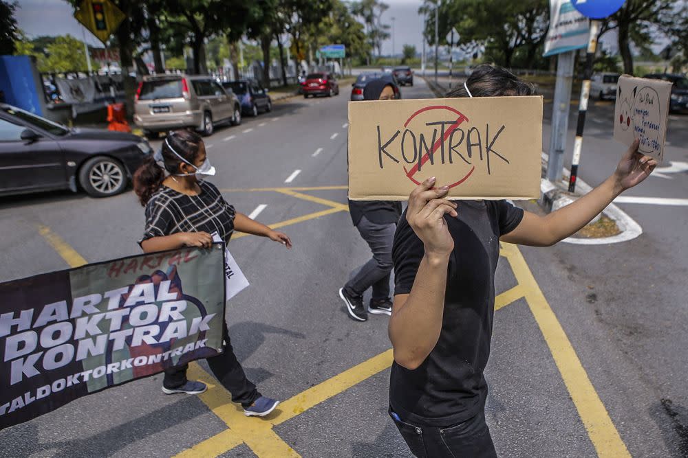 Contract doctors hold aloft placards demanding equal treatment as they go on strike at the Sungai Buloh Hospital July 26, 2021. — Picture by Hari Anggara