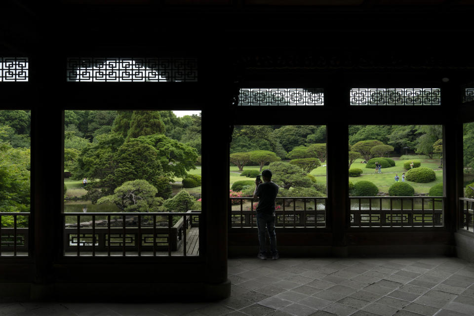 A tourist takes pictures from the Kyu Goryo-tei Pavilion in Shinjuku Gyoen national garden in Tokyo, May 31, 2019. (AP Photo/Jae C. Hong)