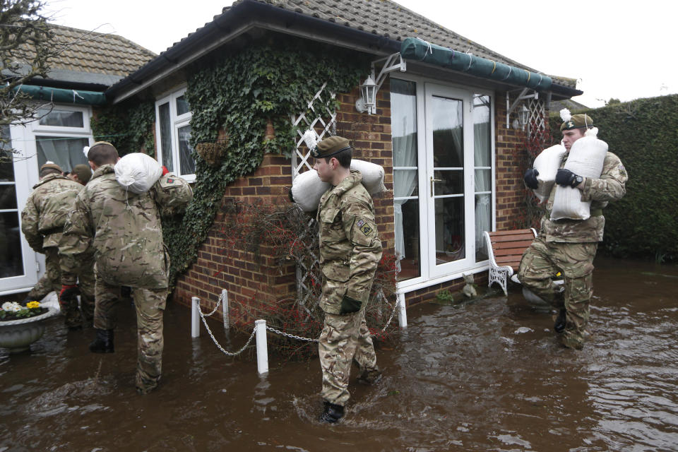 British army soldiers place sandbags at the entrance to a flooded house at Chertsey, England, Wednesday, Feb. 12, 2014. The River Thames has burst its banks after reaching its highest level for many years, flooding riverside towns upstream of London, including Chertsey which is about 30 miles west of central London. Some hundreds of troops have been deployed to assist with flood protection and to get medical assistance to the sick and vulnerable. (AP Photo/Sang Tan)