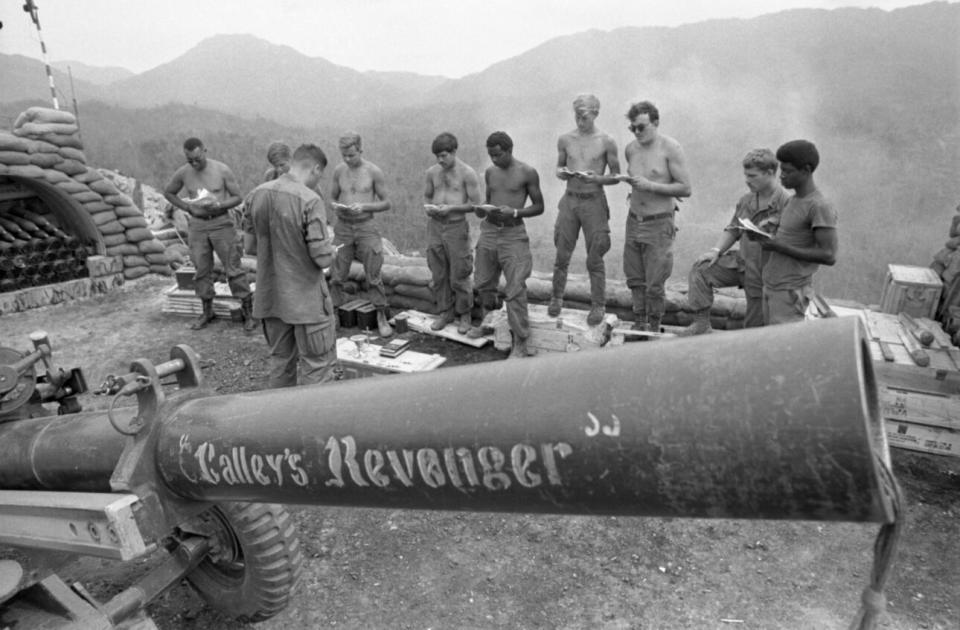 American soldiers conduct a religious service in front of an artillery weapon marked “Calley’s Revenger”, named in support of convicted mass murderer, Lt. William Calley. (Credit: Getty Images)