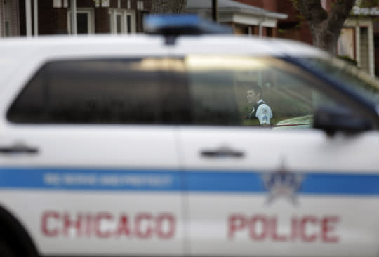 A Chicago Police officer is seen through a police vehicle window as he stands at the crime scene where a 16-year-old boy was shot in the head and killed and another 18-year-old man was shot and wounded on the 7300 block of South Sangamon Street on April 25, 2016 in Chicago, Illinois. (Photo: Joshua Lott/Getty Images)