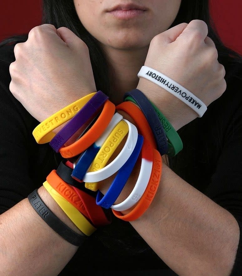 person's arms covered in plastic bracelets