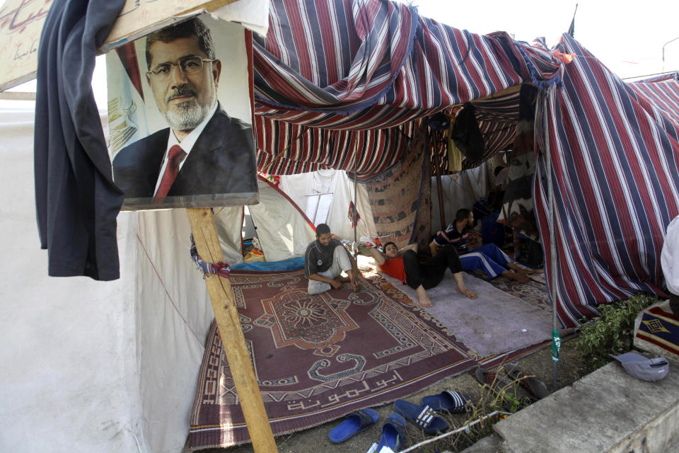 Supporters of Egypt's ousted President Mohammed Morsi, seen in the poster, rest in a tent in a park in front of Cairo University, where protesters have installed their camp in Giza, southwest of Cairo, Egypt, Thursday, Aug. 1, 2013. (AP Photo/Amr Nabil)