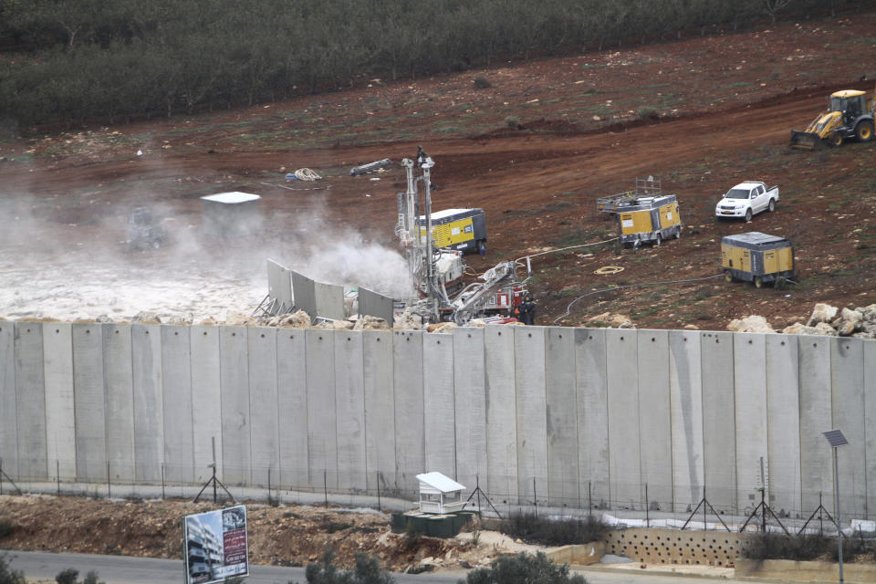 An Israeli military digger works on the Lebanese-Israeli border next to a wall that was built by Israel in the southern village of Kafr Kila, Lebanon, Tuesday, Dec. 4, 2018. The Israeli military launched an operation on Tuesday to "expose and thwart" tunnels it says were built by the Hezbollah militant group that stretch from Lebanon into northern Israel. (AP Photo/Mohammed Zaatari)