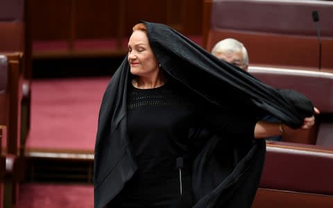 Pauline Hanson pulls off a burqa in the Senate chamber at Parliament House in Canberra - Credit:  REUTERS