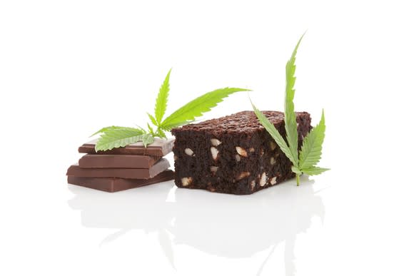 Cannabis leaves placed next to a brownie and pieces of chocolate.