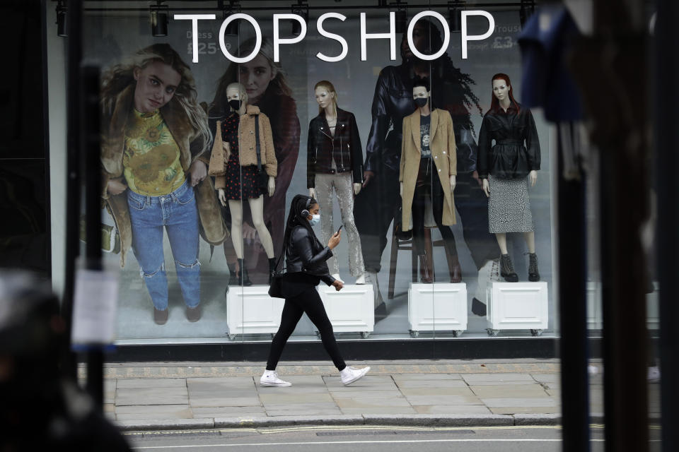 FILE - In this file photo dated Friday, Nov. 20, 2020, a woman wearing a face mask walks past mannequins wearing face masks in the window of a temporarily closed branch of the Topshop women's clothing chain during England's second coronavirus lockdown, in London. Some 15,000 retailing jobs in Britain are in peril after Arcadia Group, owner of some of the country's best-known fashion chains like Topshop, confirmed Friday Nov. 27, 2020, that it is in talks about its future. (AP Photo/Matt Dunham, FILE)