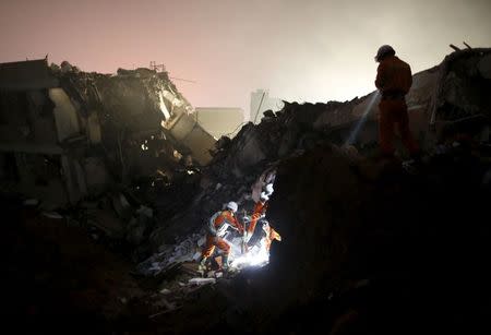 Firefighters use flashlights to search for survivors among the debris of collapsed buildings after a landslide hit an industrial park in Shenzhen, Guangzhou, China, December 20, 2015. REUTERS/Tyrone Siu