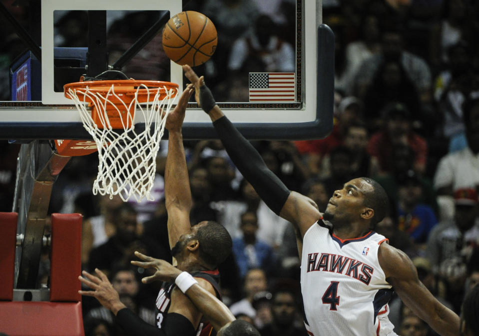 Atlanta Hawks forward Paul Millsap (4) gets his hand on a shot by Miami Heat guard Dwyane Wade (3) during the first half of an NBA basketball game on Saturday, April 12, 2014, in Atlanta. (AP Photo/John Amis)