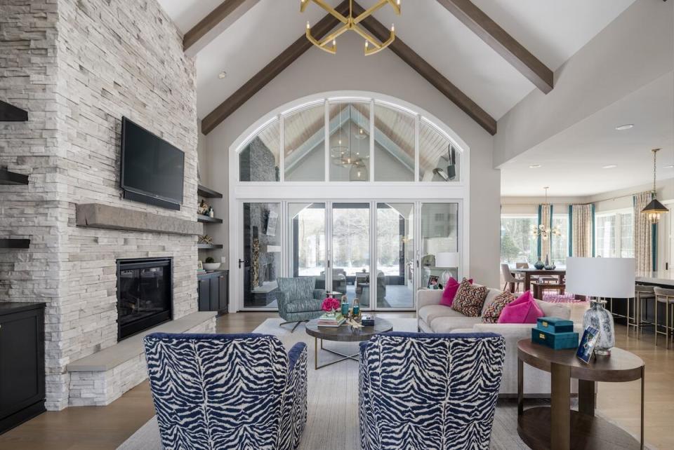 A pair of zebra-patterned chairs and pops of bright pink enliven a lofty open living space