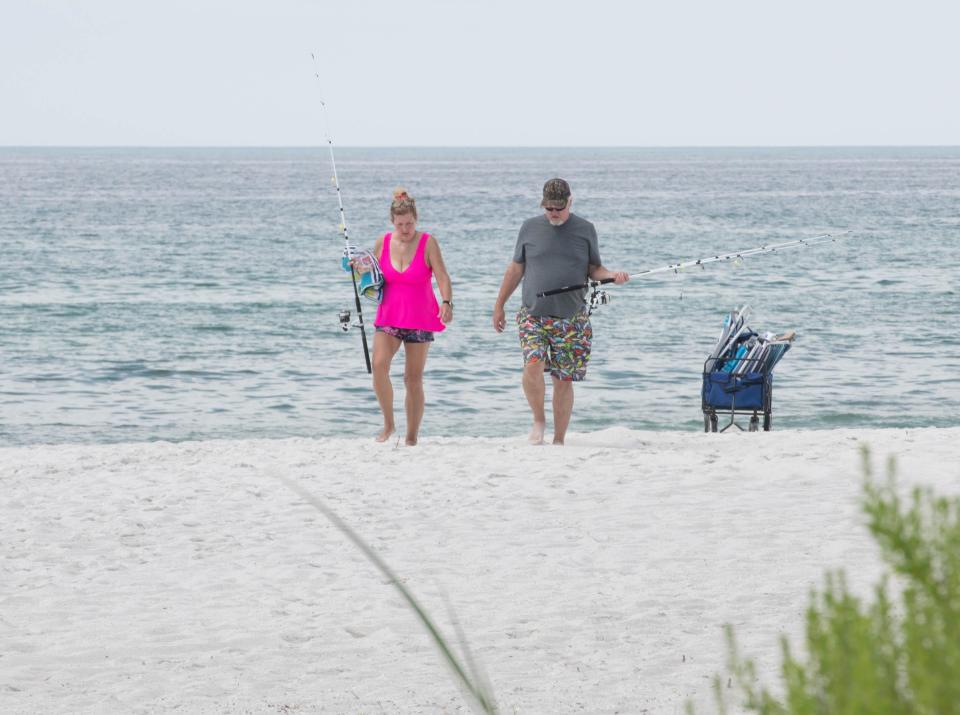 Shannon and Gil Casey, of Coldwater, Mississippi, leave the beach after fishing for catfish in the surf at Navarre Beach on Tuesday, July 11, 2023.