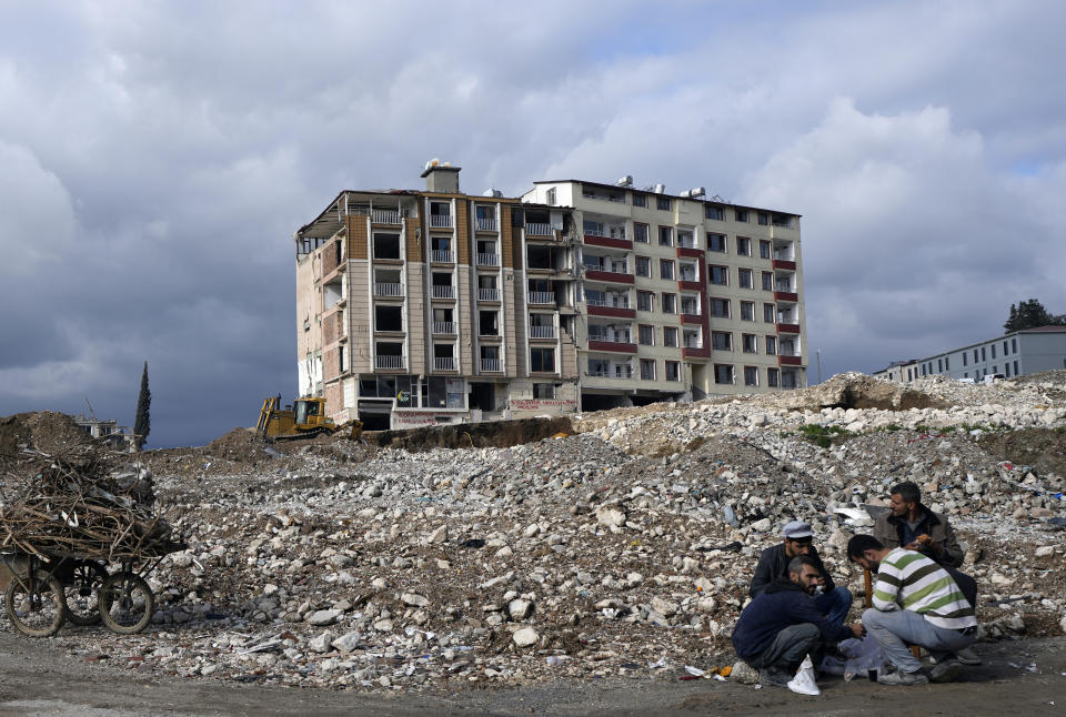 A group of workers take a break amid debris after removing furniture from a nearby building that was damaged by the Feb. 6, 2023 earthquake in the city of Antakya, southern Turkey, Thursday, Jan. 11, 2024. A year after a powerful earthquake struck reducing hundreds of thousands of homes to rubble, many in the region are struggling to rebuild lives. (AP Photo/Khalil Hamra)