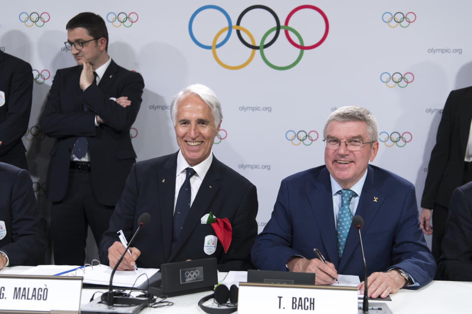 International Olympic Committee (IOC) president Thomas Bach, right, from Germany and Italy's National Olympic Committee (CONI) president Giovanni Malago, left, pose signing documents with Italian delegation after Milan-Cortina won the bid to host the 2026 Winter Olympic Games, during the first day of the 134th Session of the International Olympic Committee (IOC), at the SwissTech Convention Centre, in Lausanne, Switzerland, Monday, June 24, 2019. Italy will host the 2026 Olympics in Milan and Cortina d'Ampezzo, taking the Winter Games to the Alpine country for the second time in 20 years. (Laurent Gillieron/Keystone via AP)