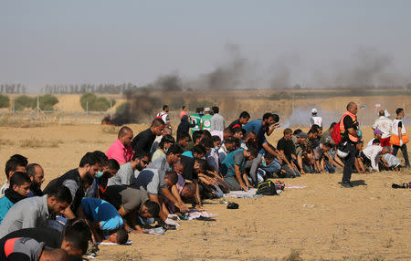 Palestinians pray during a protest demanding the right to return to their homeland at the Israel-Gaza border, in the southern Gaza Strip August 17, 2018. REUTERS/Ibraheem Abu Mustafa