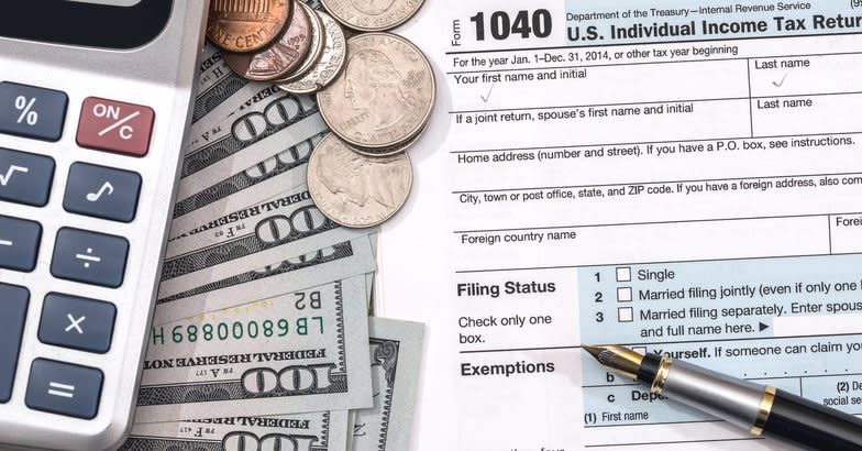 U.S. 1040 tax return form with dollar, pen and calculator.