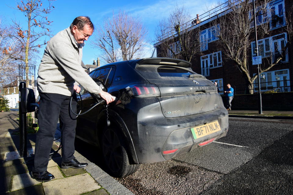 Electric Connected Kerb customer Ged O&#39;Sullivan plugs an electric vehicle into one of the charging infrastructure company&#39;s smart public on-street chargers in the borough of Hackney, London, Britain, January 12, 2022. Picture taken January 12, 2022. REUTERS/Nick Carey