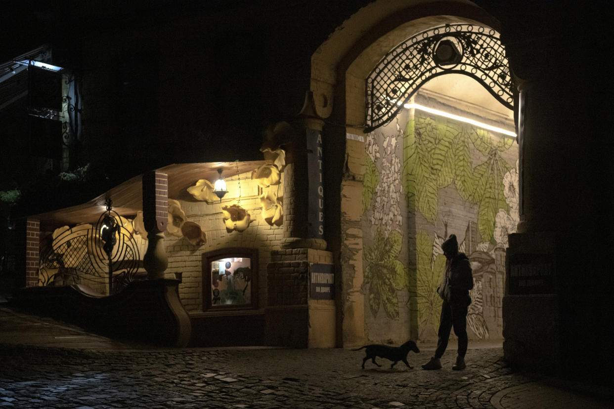 FILE - A woman walks her dog during a blackout in Kyiv, Ukraine, Friday, Nov. 4, 2022. The situation in Ukraine's capital, Kyiv, and other major cities has deteriorated drastically following the largest missile attack on the country's power grid on Tuesday, Nov. 15, 2022. Ukrainian state-owned grid operator Ukrenergo reported that 40% of Ukrainians were experiencing difficulties, due to damage to at least 15 major energy hubs across the country. (AP Photo/Andrew Kravchenko, File)