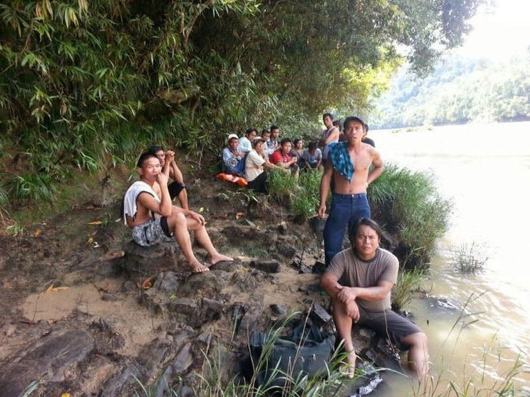 Passengers who survived after their overloaded boat capsized rest on the riverbank in Belaga, in Malaysia's Sarawak state on the island of Borneo, on May 28, 2013. About 12 people were still believed missing but the exact number remained unclear due to the lack of a passenger manifesto for the vessel