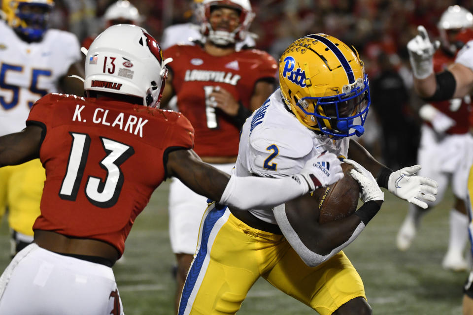 Pittsburgh running back Israel Abanikanda (2) avoids the grasp of Louisville defensive back Kei'Trel Clark (13) during the first half of an NCAA college football game in Louisville, Ky., Saturday, Oct. 22, 2022. (AP Photo/Timothy D. Easley)